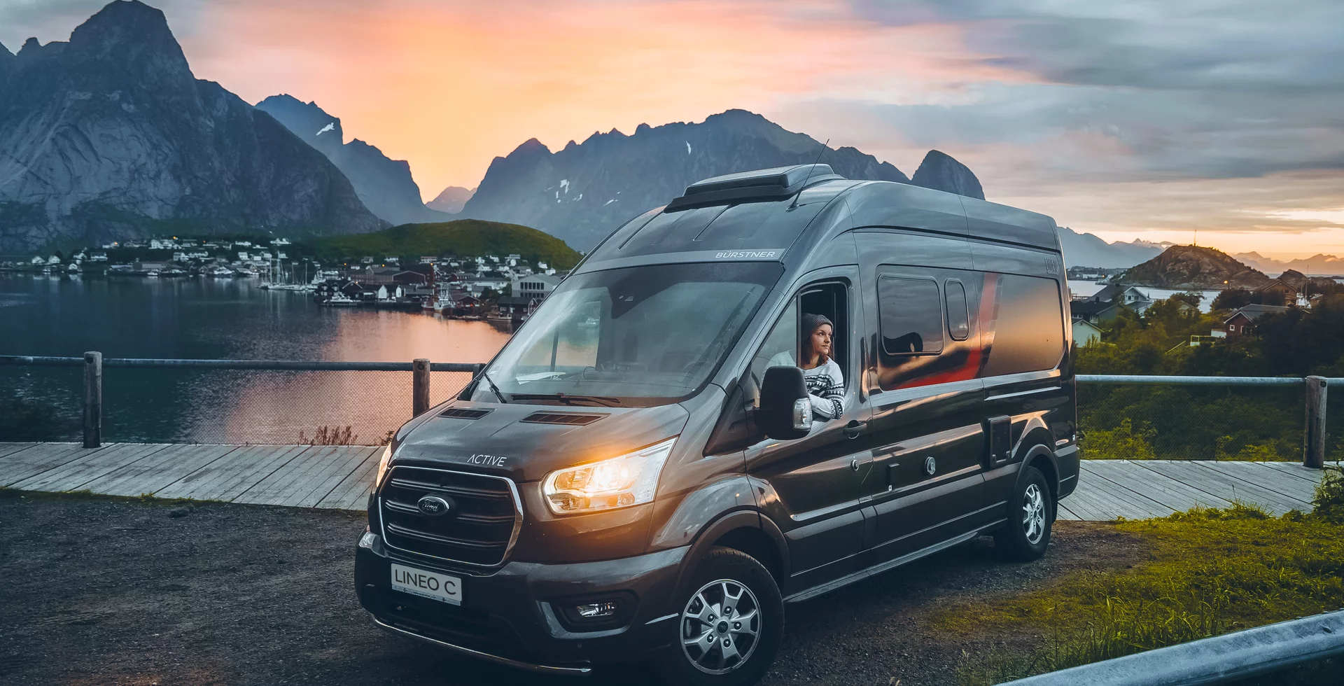Ein Bürstner Lineo C Campervan steht vor einer malerischen Berg- und Seelandschaft bei Sonnenuntergang.