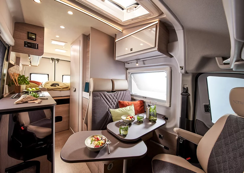 Innenraum eines Lineo Campervans mit Tisch, Sitzbereich und Küche.