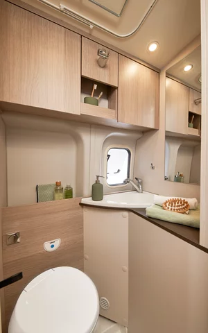 Ein modernes Wohnmobil-Badezimmer mit Toilette, Waschbecken und Stauraum.