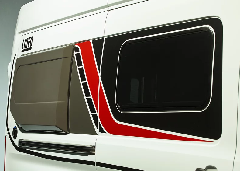 Seitliche Ansicht eines Lineo Wohnmobils mit markanten roten und schwarzen Streifen.