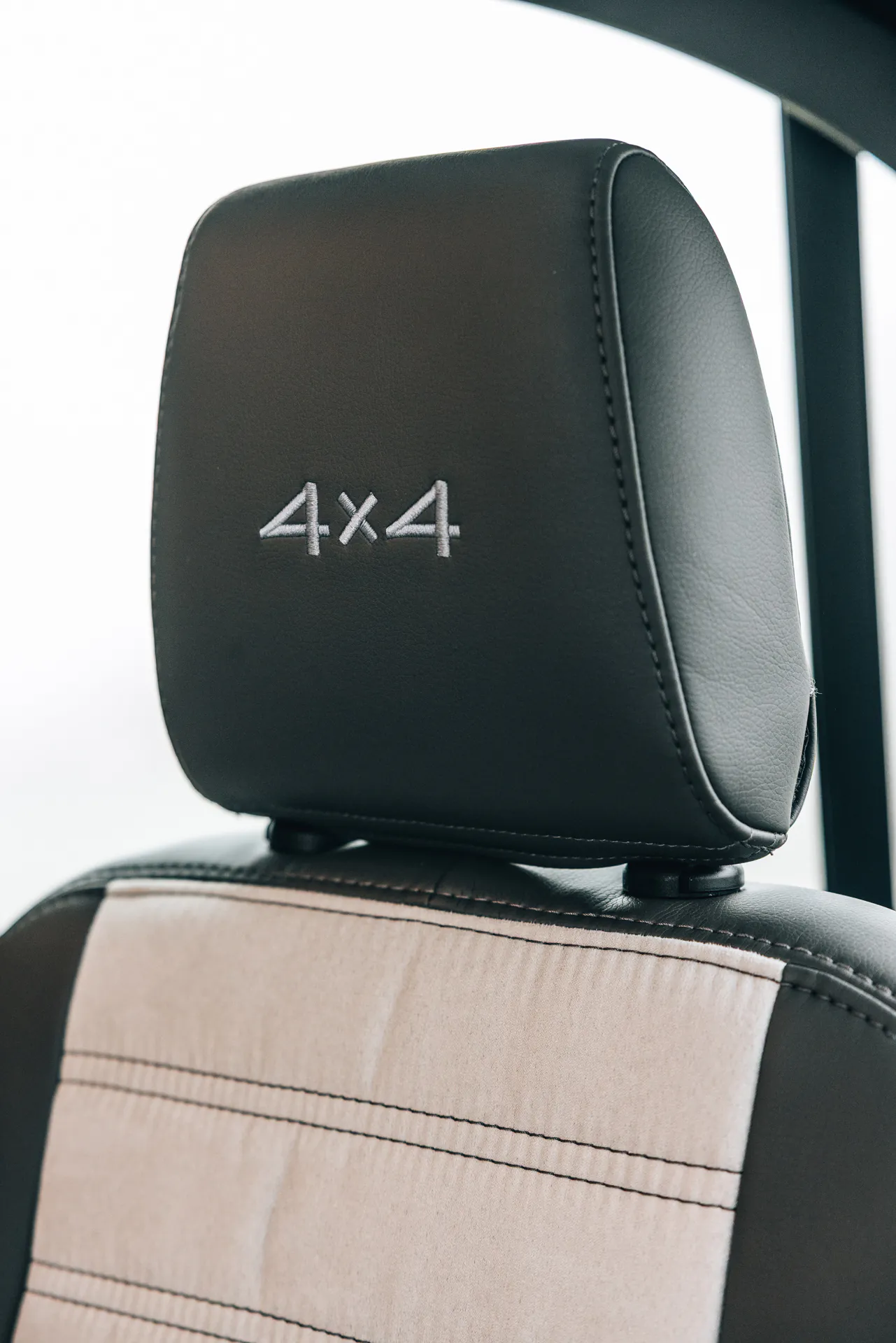 Schwarze Kopfstütze mit "4x4"-Stickerei in einem Fahrzeug.