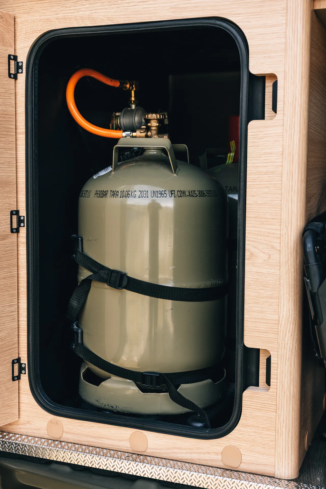 Gasflasche in einem Holzfach eines Campers gesichert.