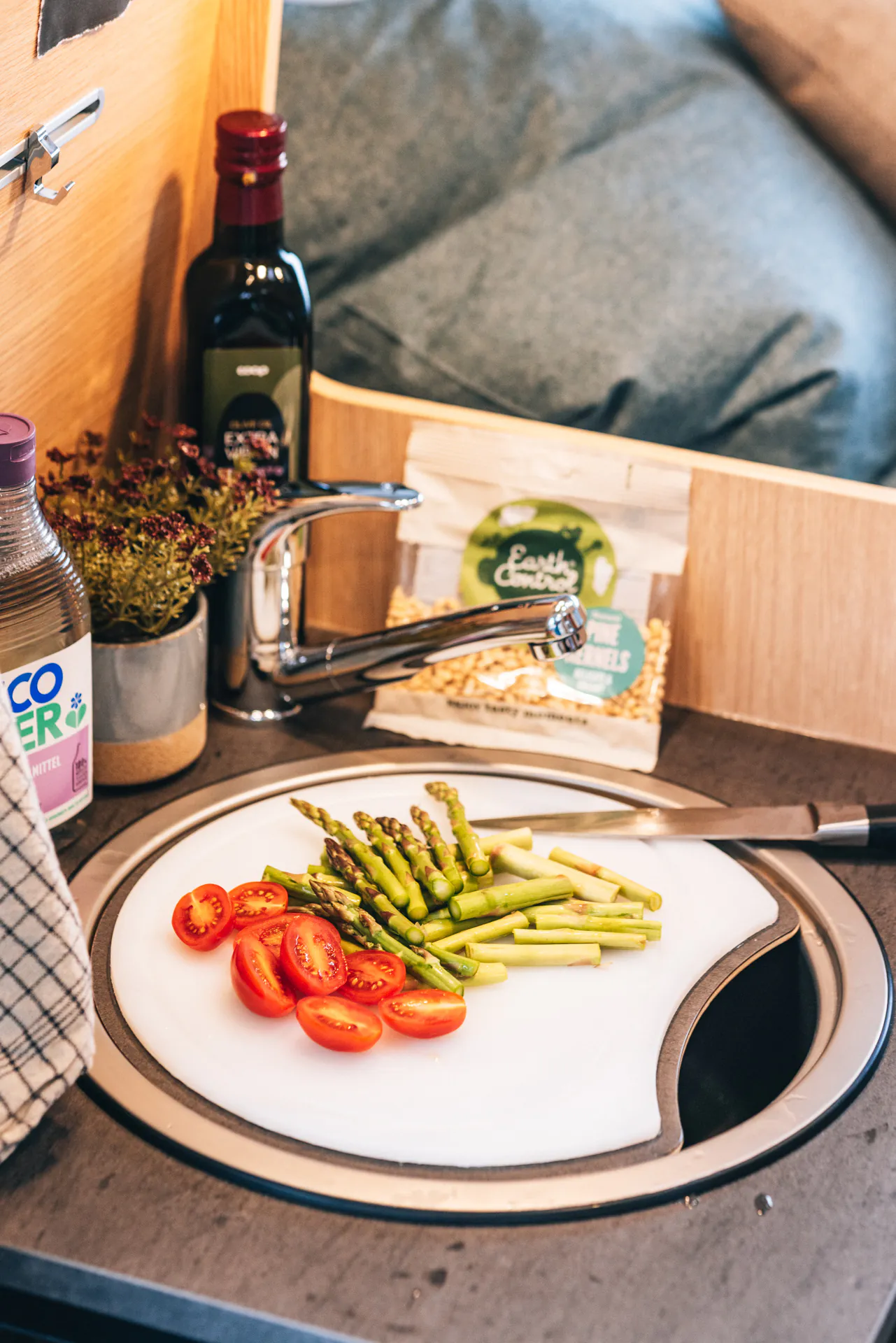 Küchenzeile mit geschnittenem Spargel und Tomaten auf einem Schneidebrett.