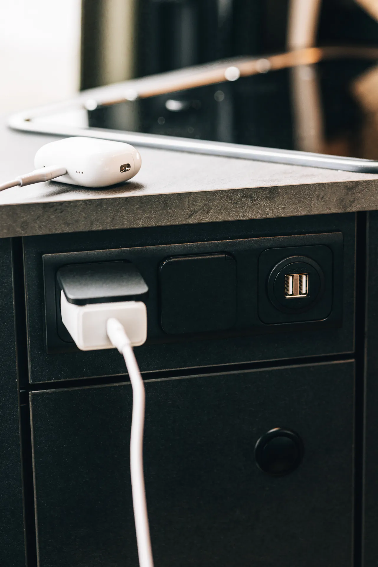 Steckdose mit USB-Anschluss und Ladekabel in einer Küchenzeile.