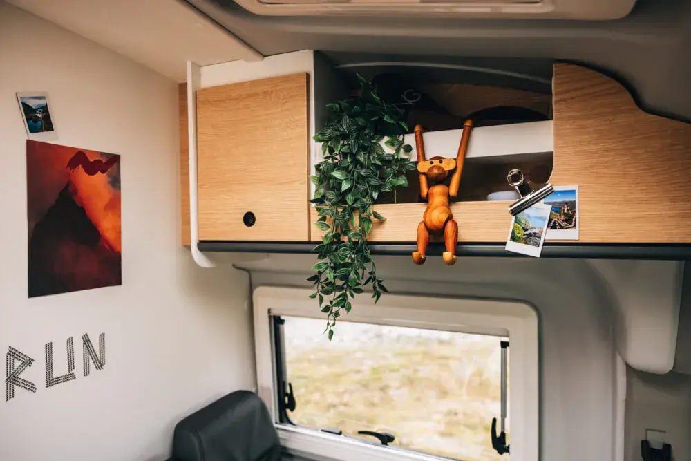 Innenraum eines Wohnmobils mit Holzregalen, Pflanzen und Dekorationen.